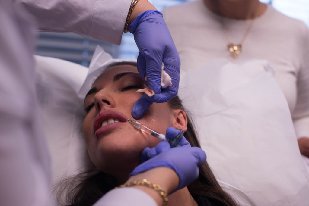 Woman getting dermal filler injection in lips
