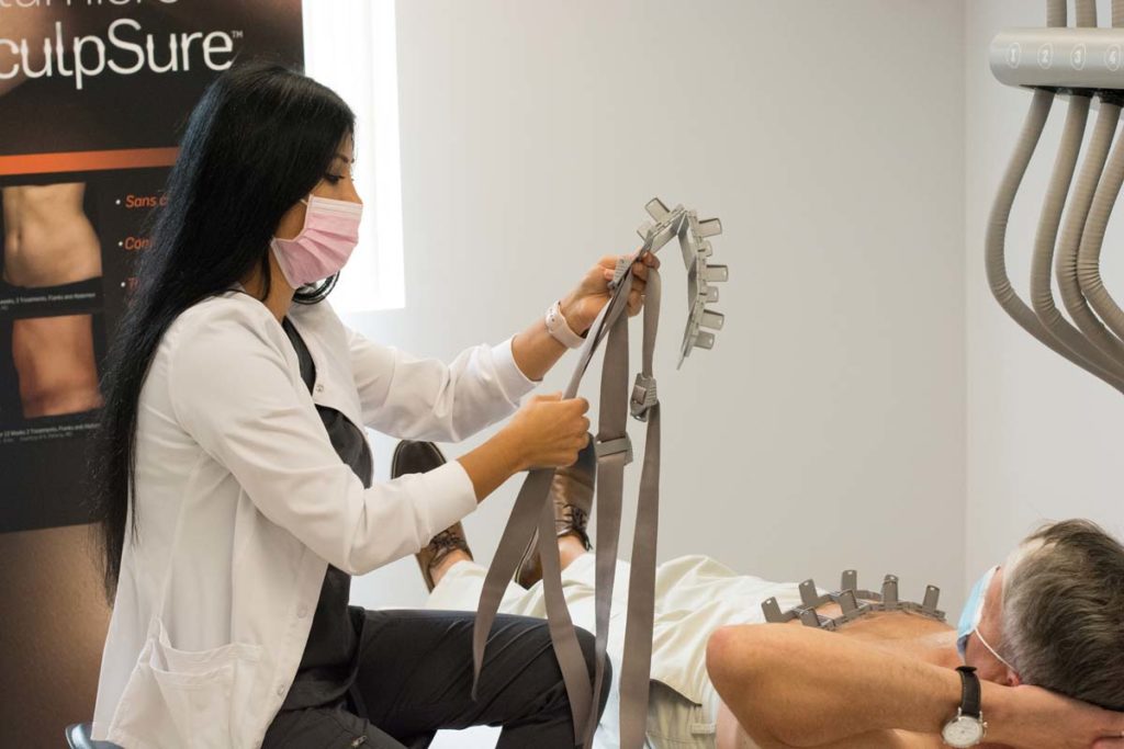 Female technician preparing male patient for sculpsure treatment